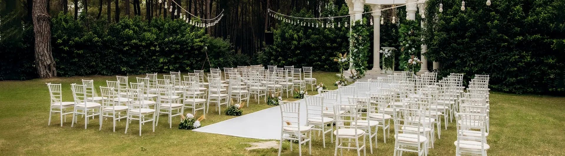 Çim alanda nikah için dizilmiş beyaz sandalyeler ve beyaz yürüyüş halısı