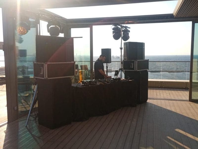 Deniz kenarındaki terasta gün ışığında DJ kabini ve tavana asılı hareketli ışıklar