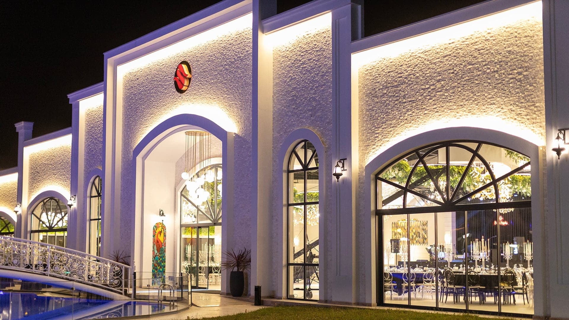 Kemerli büyük camları ve ışıklı beyaz cephesiyle salonun girişi