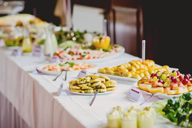 Beyaz örtülü açık büfede meyve, börek ve meze tabakları