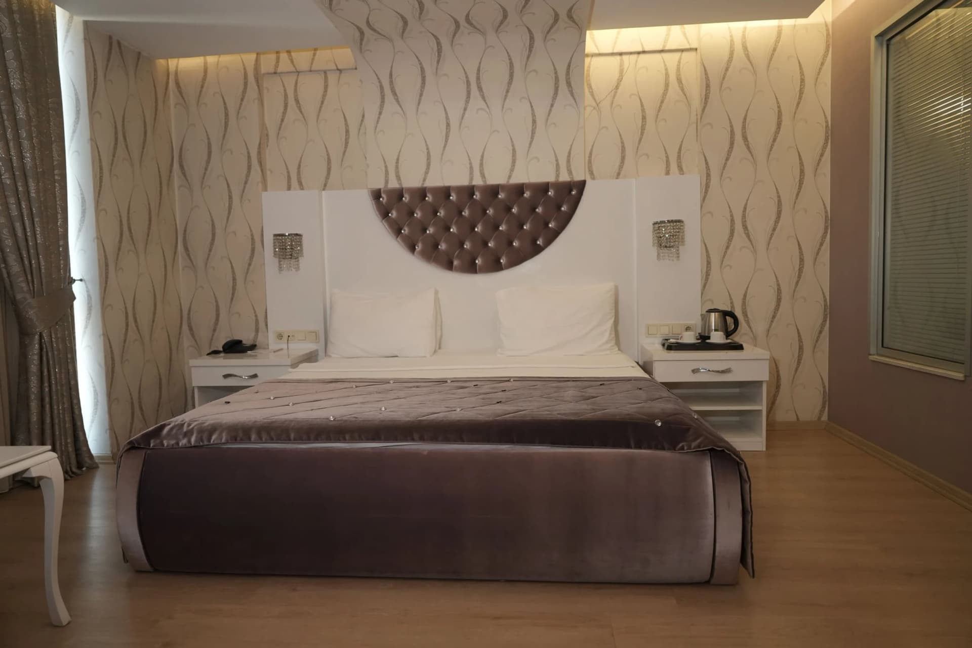 Süit odada kapitone başlıklı çift kişilik yatak ve desenli duvar kağıdı