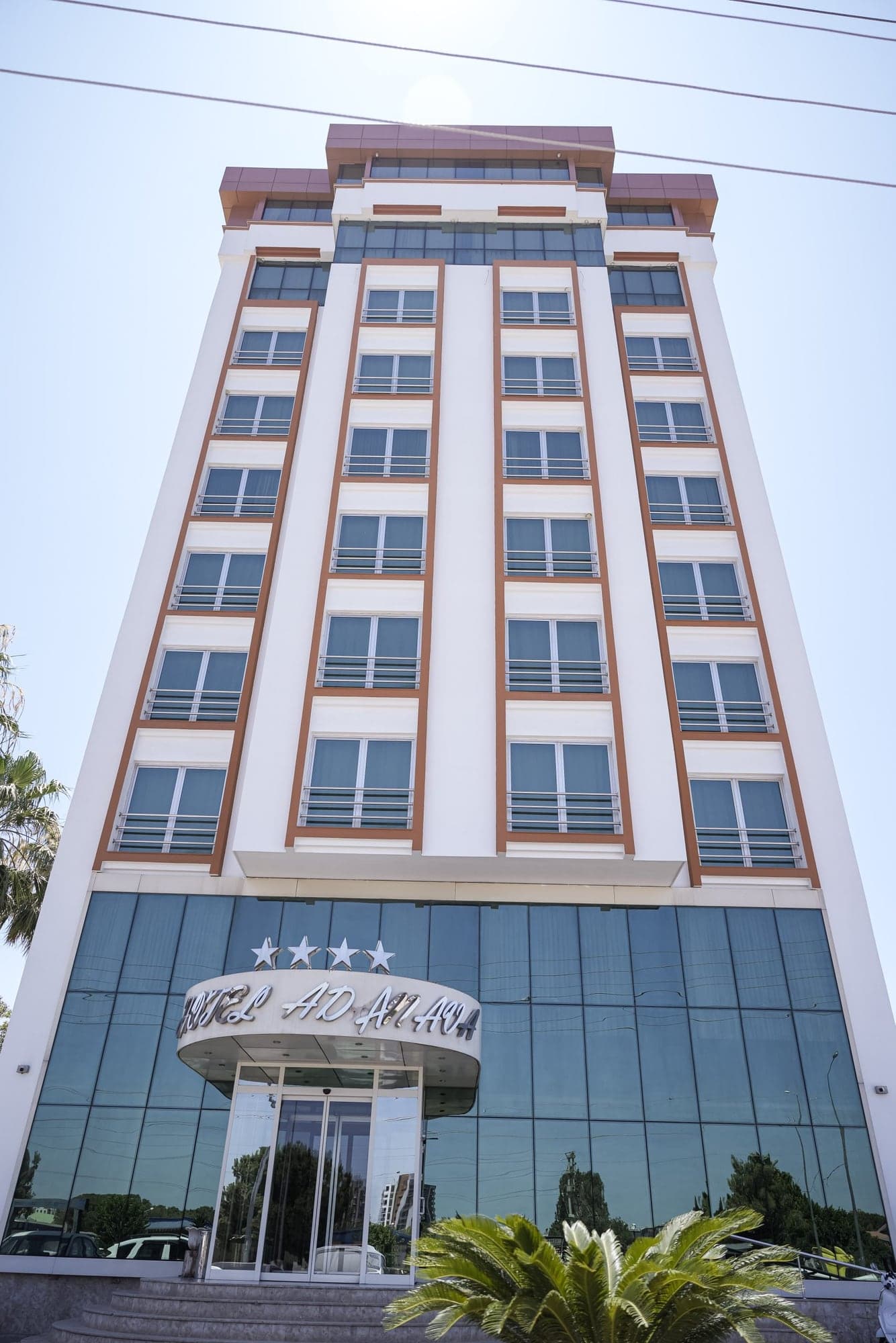 Hotel Adanava'nın cam girişli, çok katlı otel binası cephesi