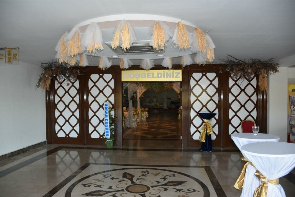 Hoş geldiniz yazılı salon kapısı, mermer desenli zemin ve kokteyl masaları
