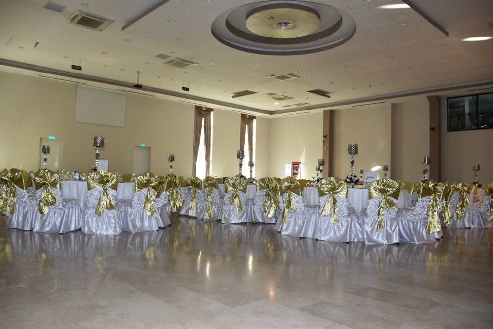 Yuvarlak masaların altın rengi kurdeleli sandalyelerle çevrelendiği geniş salon