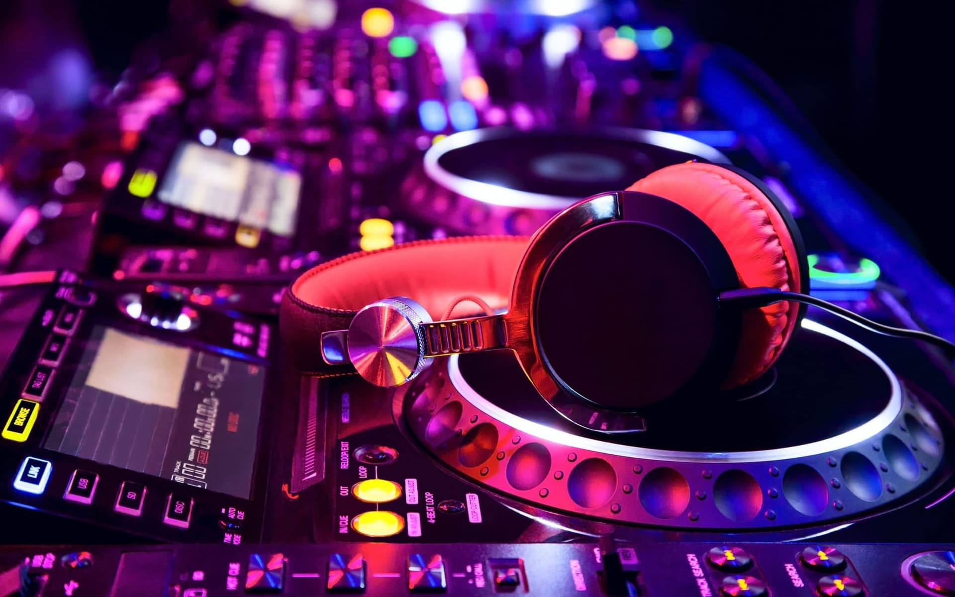 DJ kontrol cihazının çalar plakası üzerinde duran kırmızı kulaklık, mor sahne ışığında