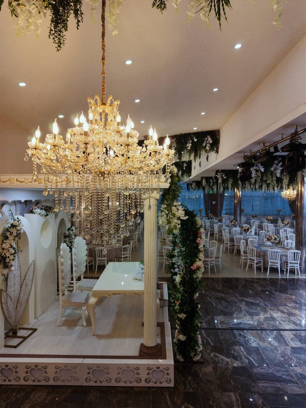 Silver Salon'da kristal avizeli, çiçek sarmaşıklı gelin damat masası