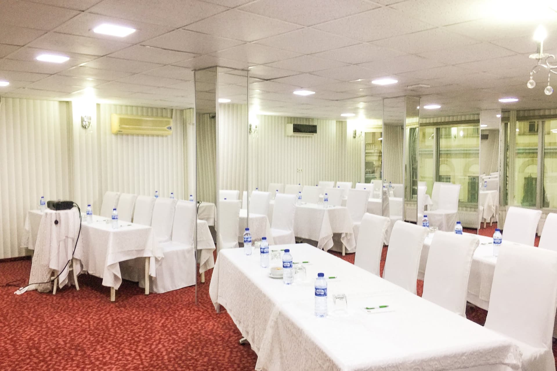 Beyaz kılıflı sandalyeler ve örtülü uzun masalarla kurulmuş salon düzeni