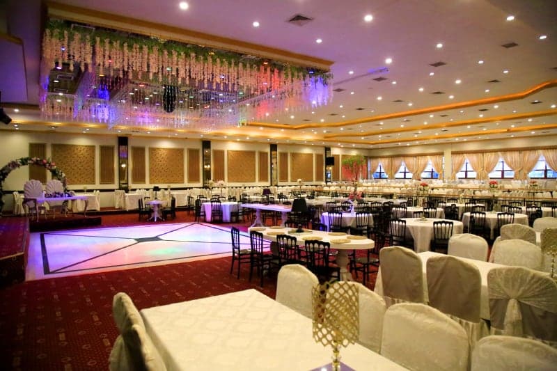 Sultan II'de kristal sarkıtlı tavan altında ışıklı dans pisti ve beyaz giydirilmiş sandalyeler