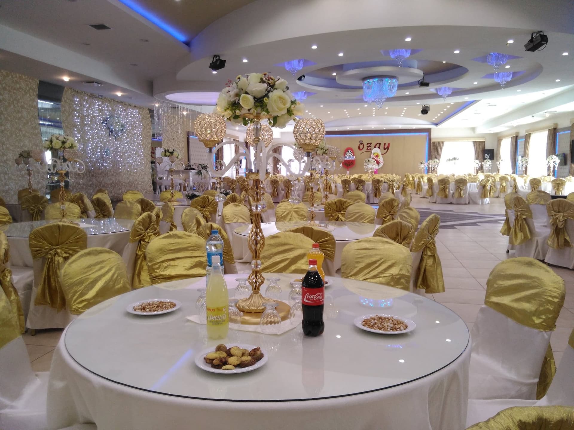 Altın sandalye kılıfları ve kristal şamdanlı orta süsle hazırlanmış yuvarlak masa