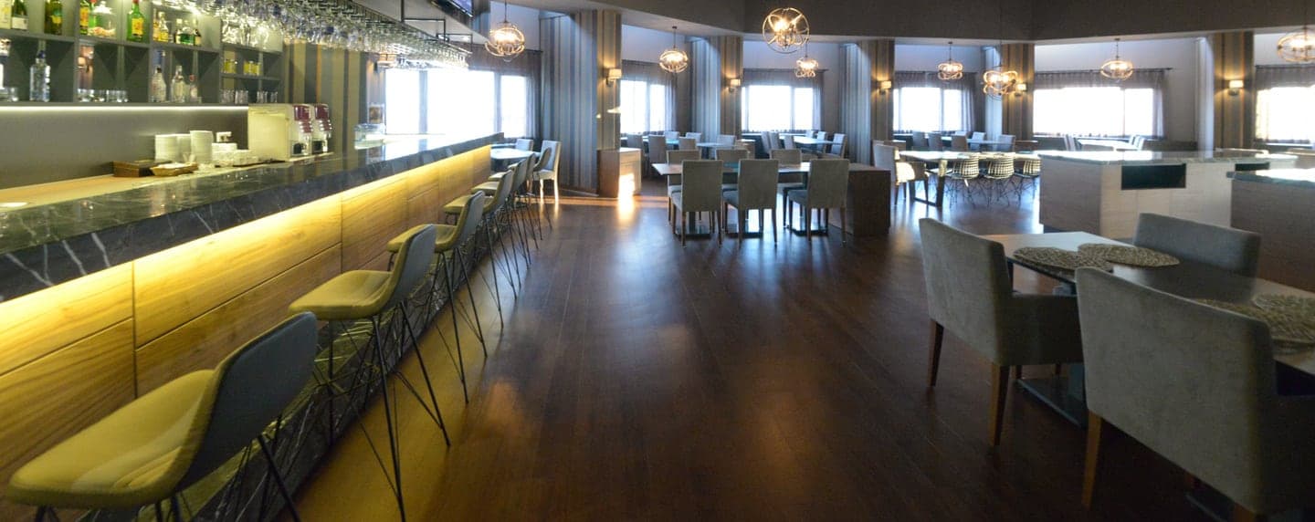 Ahşap zeminli restoranda ışıklı bar tezgahı ve masa grupları