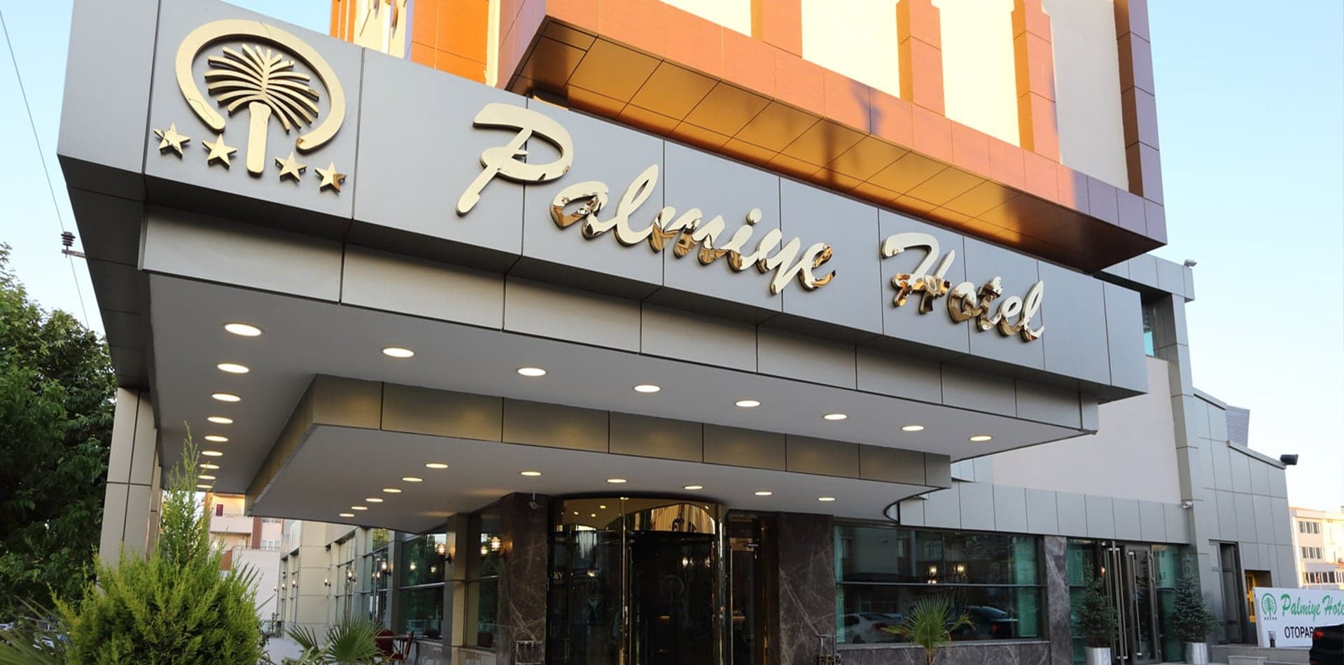 Palmiye Hotel giriş cephesi, saçak altındaki döner kapı ve tabela