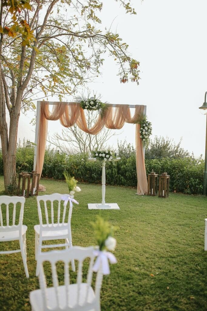 Gardenya Bahçe'de şeftali rengi tüllerle süslü nikah takı ve beyaz sandalyeler