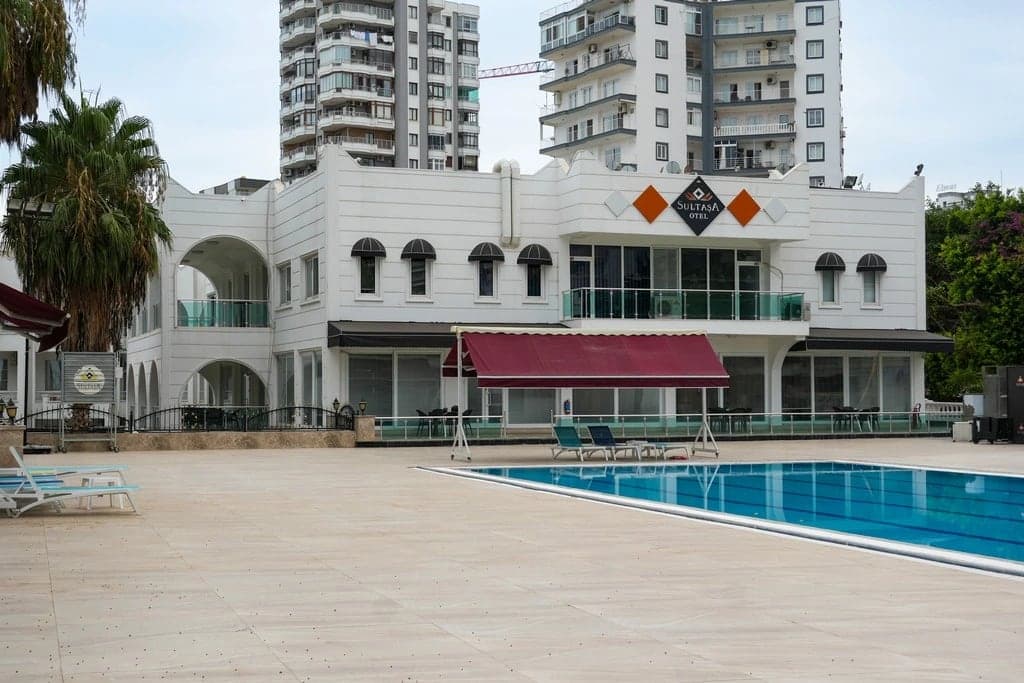 Sultaşa Hotel'in beyaz cepheli binası ve önündeki havuz