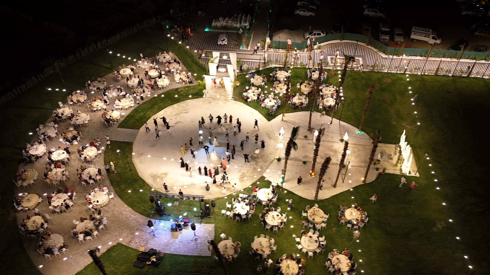 Gece havadan bahçe: ışıklı yuvarlak dans pistinin çevresine dizilmiş dolu masalar