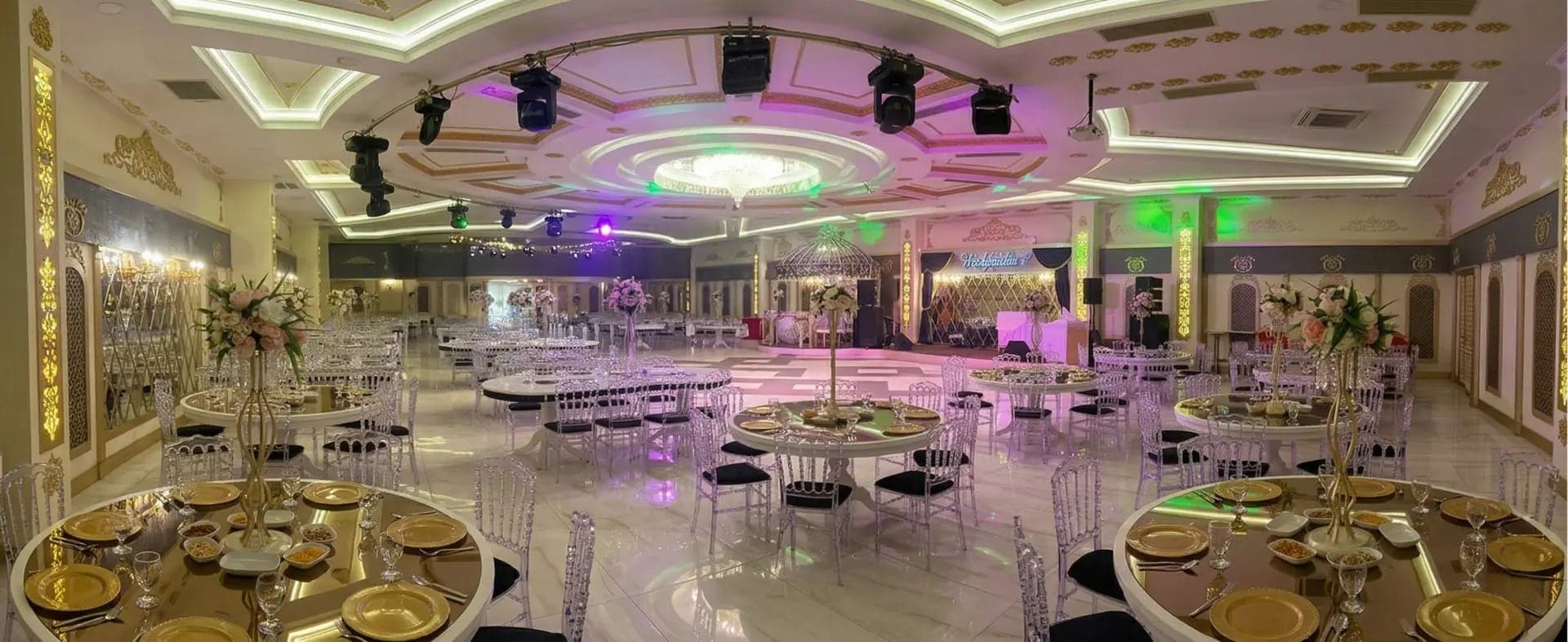 Altın servis tabaklı yuvarlak masalar, robot ışıklar ve sahneyle kurulmuş geniş salon